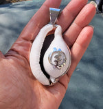 Cowrie shell pendant featuring a sterling silver Adinkra symbol known as Gye Nyame.