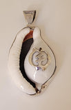 Cowrie shell pendant featuring a sterling silver Adinkra symbol known as Gye Nyame.