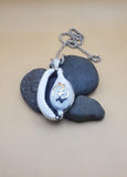 Cowrie shell pendant featuring a sterling silver Adinkra symbol known as Gye Nyame.